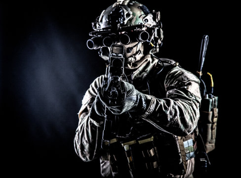 Army soldier aiming rifle in camera in darkness