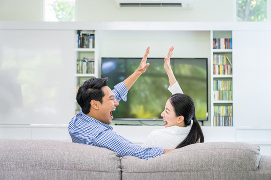 Back View Of An Asian Couple Happy Watching Tv Together