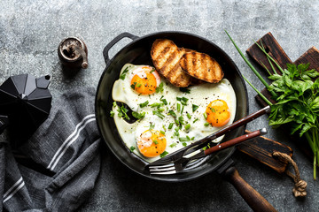 fried eggs in a cast iron pan top view - obrazy, fototapety, plakaty