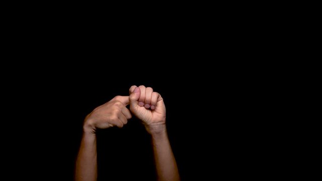 A pair of hands against a black background make an obscene gesture of a sexual nature