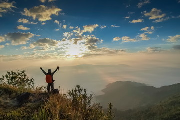 Obraz na płótnie Canvas Silhouette a Photographer standing on top hill around with sea of fog and cloudy sky background, sunrise at Pha Tang, Chiang Rai, northern of Thailand.