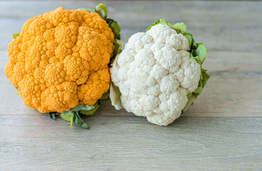 On a gray background cauliflower of two colors orange and white,