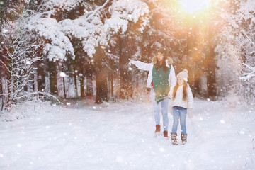 Young family for a walk. Mom and daughter are walking in a winter park.