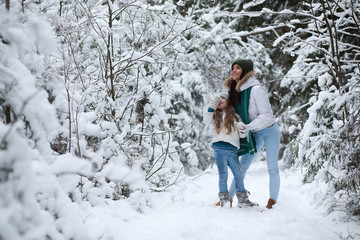 Young family for a walk. Mom and daughter are walking in a winter park.