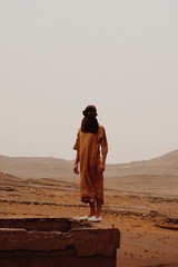 Fototapeta na wymiar Hombre observando en el desierto con chilaba marron y turbante 