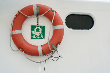 A lifebuoy, ring buoy, lifering, lifesaver, life donut, life preserver on the white wall of boat or...