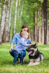 Family walk: mother and son with their dog in a city park for a walk. A child stroking a dog. German shepherd is the best friend of the child.