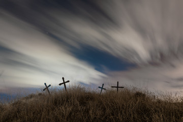 The spirit on Halloween Night flying over a cemetery. Dramatic sky with moon, clouds and stars.