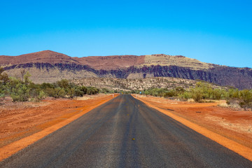 Unmarked freshly paved road leading straight towards mountain wall at Karijini National Park