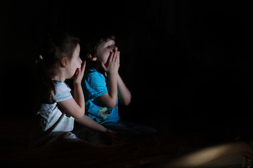 Small children in a dark room watching TV