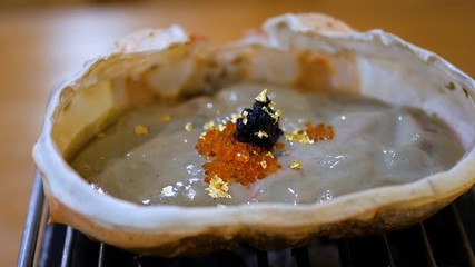 Zoom in of Kani Miso, crab miso, crab fat boiling / grill on the stove at the restaurant (Japanese Food)