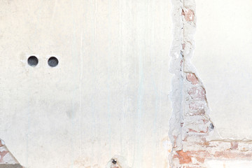Old wall with paint, bricks, holes and crack on it that can be used as background or texture