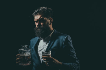 Attractive Bartender in whiskey bar. Stylish rich man holding a glass of old whisky. Man with beard...