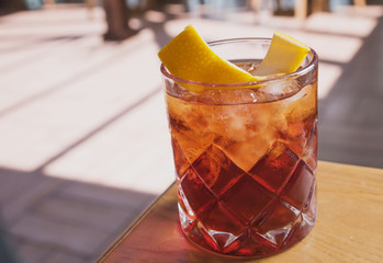 cocktail with soda, whiskey and orange zest on the background of a summer cafe on a wooden table