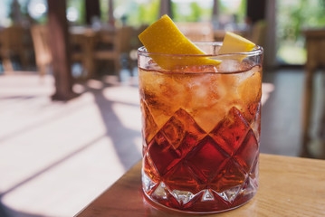 cocktail with soda, whiskey and orange zest on the background of a summer cafe on a wooden table