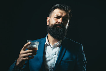 Fashion style concept. Tasting and degustation concept. Barman or Bartender serves cognac. Bearded handsome man holding glass of whiskey.