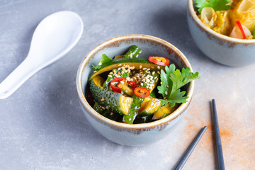 Korean salad kimchi with beaten cucumbers with garlic, chili pepper, soy sauce and sesame oil. Healthy food salad bowl. Healthy balanced appetizer plate. flat lay with salad, chopsticks on grey salad