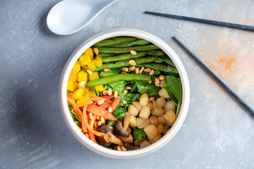 Pan asian cuisine. salad with scallop, beans, mango, asparagus, spinach. Flat lay with white bowl with salad, chopsticks on grey stone background. Healthy, balanced food. Seafood. buddha bowl salad