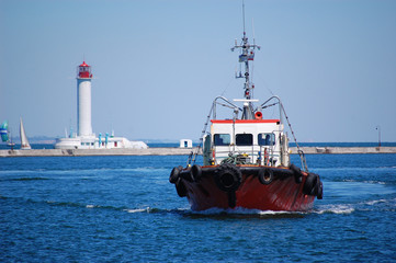pilot boat in port against the background of a lighthouse