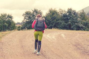 Travel adventure woman with a backpack hiking through forest path. Travel concept.