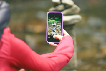 Woman hiker taking photo with cell phone of stones in the mountains