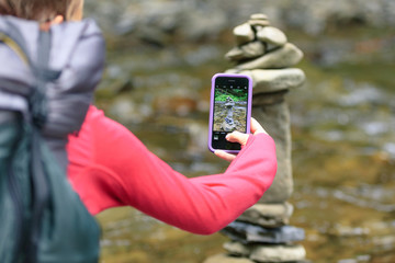 Girl taking photo of stones using cell phone in the mountains