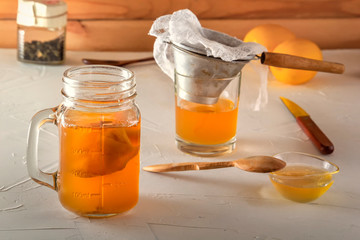 Homemade fermented drink Kombucha in glass jars with lemon, honey and ginger on a wooden table.