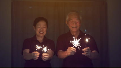 Asian senior couple playing sparklers, fire cracker at night. Concept celebrating life