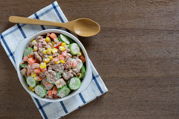 top view of tuna and vegetables salad in a ceramic bowl on wooden table, copy space. homemade style food concept.