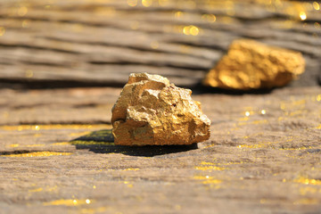 close up pure gold minerals with golden light on old wooder background, investment and business concept