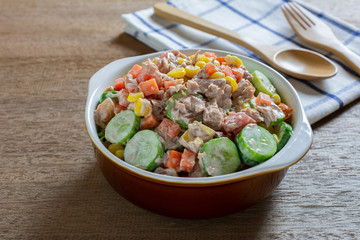 close up of tuna and vegetables salad in a ceramic bowl on wooden table. homemade style food concept.