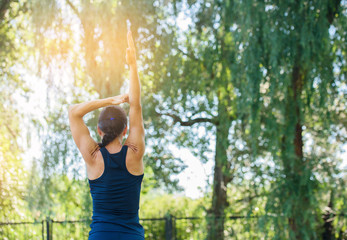 Athletic girl working out in a park. Beautiful embossed back.