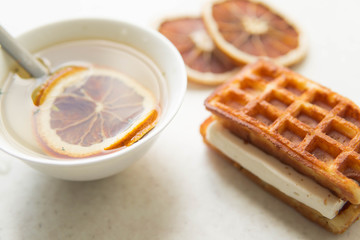 Sweet belgium waffles with souffle and green tea and slices of dry orange