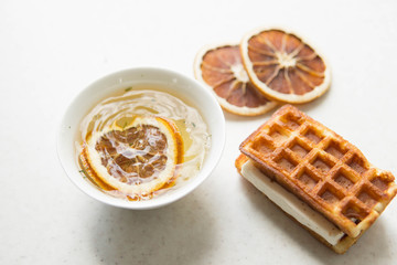 Sweet belgium waffles with souffle and green tea and slices of dry orange