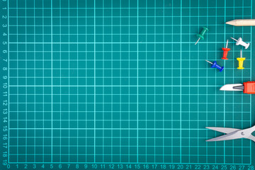 Knives cutter, pencil, scissor and stationary on white green cutting mat background. Selective focus and copy space
