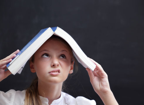 Giovane studente con un libro sopra la testa