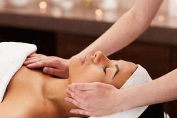 Side view of beautiful mixed-race woman enjoying face massage in luxury spa, copy space