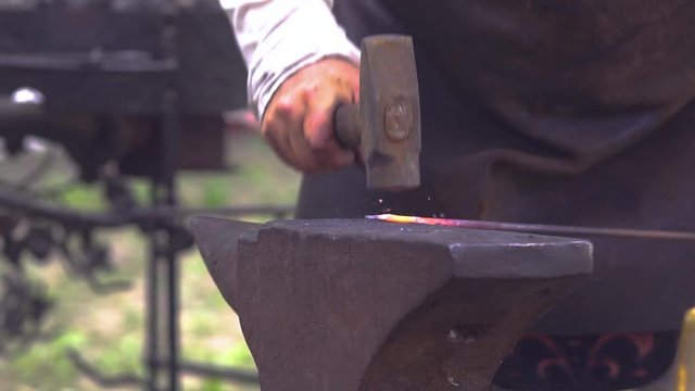 Blacksmith hitting glowing hot metal rod. Presentation at Slavic and old culture days in Sobotka, Poland. Slow motion.