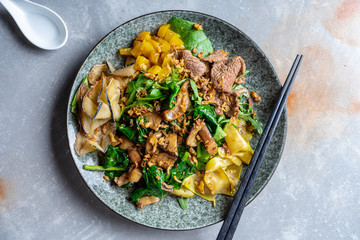 Top view pan-asian thai salad bowl. Flat lay food on grey stone background. Warm salad with veal, spinach, mushrooms and spices. Copy space. Banner, menu, poster photo