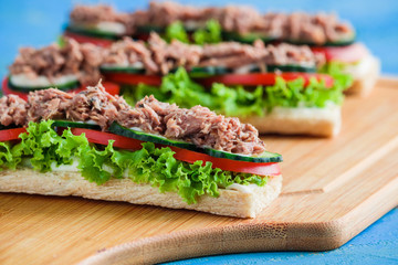 open sandwiches with crispbread slice lettuce cucumber tomato tuna oncutting board close up