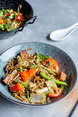 Close up view on soba noodles with sweet and sour sauce, vegetables in grey bowl. Pan-asian food flat lay. pho noodle and soba in bowl. Copy space. Menu, banner or poster. vegan food