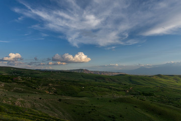 Beautiful landscape, green fields and cloudy sky at the sunset.