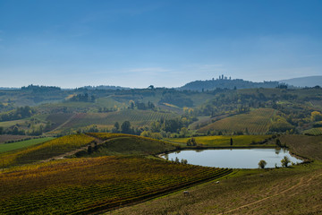 Fototapeta na wymiar Tuscany vineyards landscape with lake and San Gimingano at the background