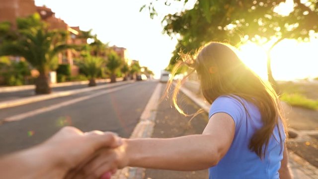 Follow me - happy young woman pulling guy's hand - hand in hand running on a bright sunny day. Shooted at different speeds: normal and slow