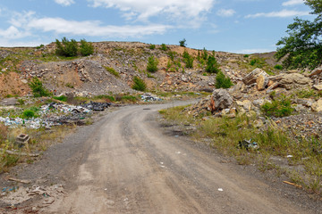 The illegal garbage dump on the roadside in the old abandoned stone quarry