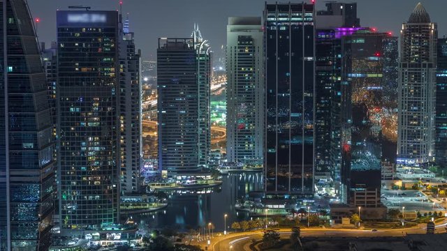 Jumeirah Lake Towers residential district aerial night timelapse near Dubai Marina. Illuminated modern skyscrapers and traffic from above