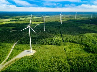 Aerial view of windmills in summer forest in Finland. Wind turbines for electric power with clean...
