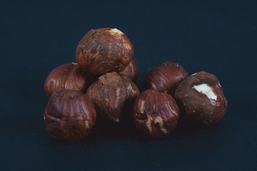 A small pile of peeled hazelnuts on a black background. Side view. Close-up. Macro