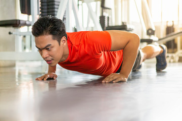 Muscular bodybuilder guy doing push ups exercise  in fitness gym . young sport asian man training . workout