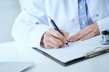 Female medicine doctor hand holding silver pen writing something on clipboard closeup.. Ward round, patient visit check, medical calculation and statistics concept. - obrazy, fototapety, plakaty